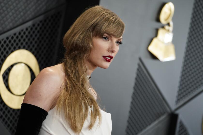 Taylor Swift poses in a white gown and black gloves at the Grammy Awards