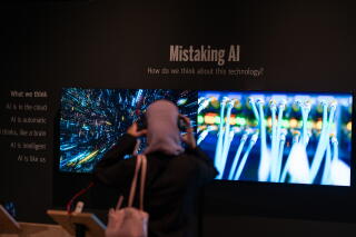A visitor listens to the audio component of an exhibit titled Mistaking AI