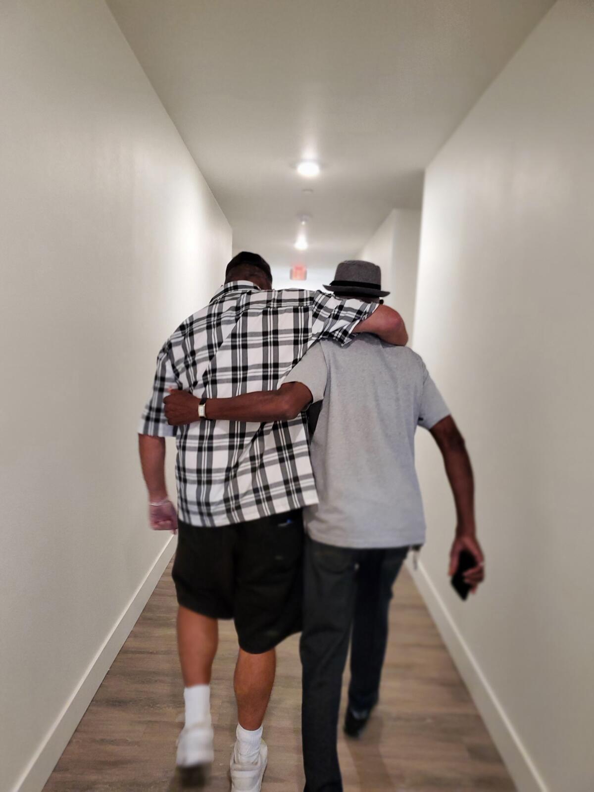 Two formerly homeless veterans walk in the hallway at Jamboree's Heroes Landing in Santa Ana.