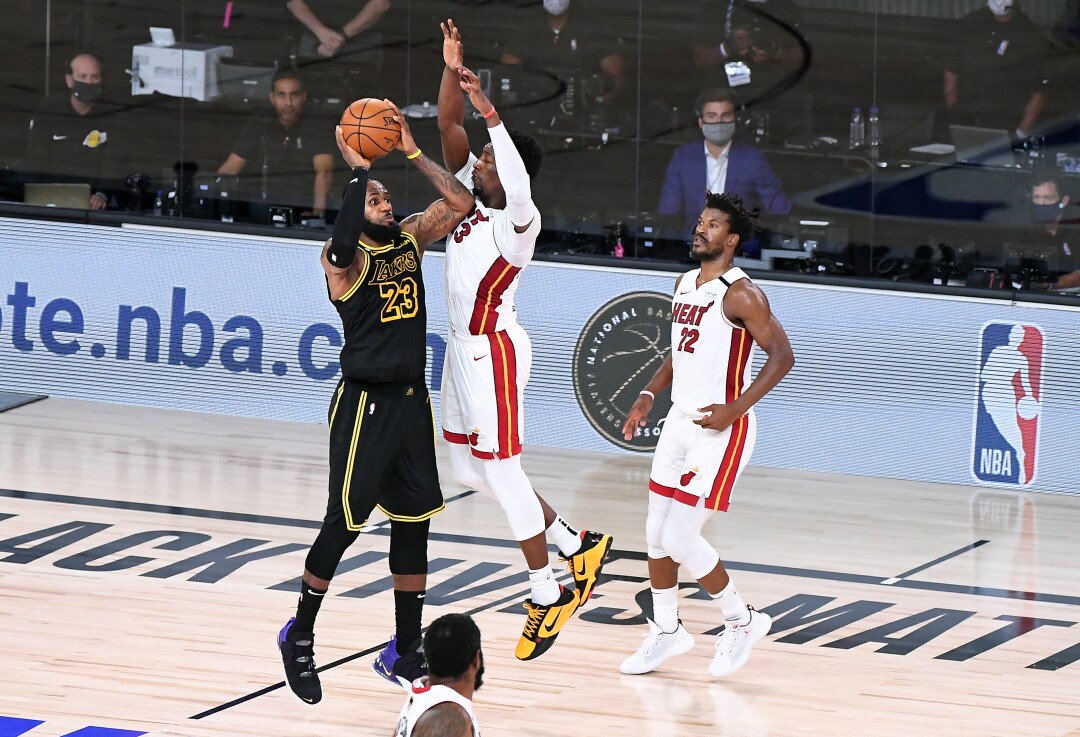 Lakers forward LeBron James shoots a three-pointer with under two seconds left as Miami Heat forward Bam Adebayo defends.