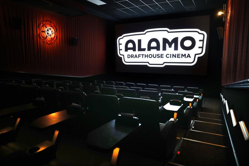An empty movie theater with a screen showing the logo for Alamo Drafthouse Cinema