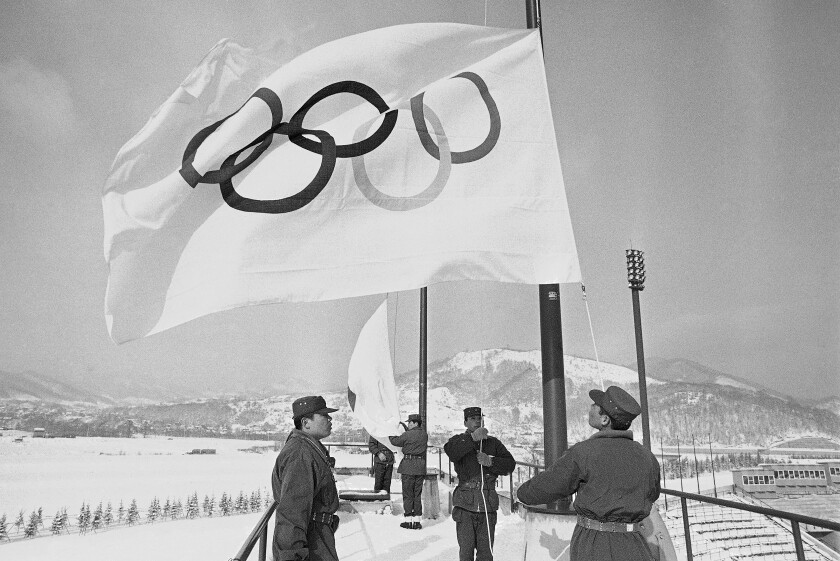 FILE - Members of Japan's self defense ground forces raise Olympic Flags on Sunday, Jan. 23, 1972, in Sapporo at Makomanai speed skating stadium in rehearsal of ceremony to take place February 3 at official opening of Winter Olympic. The northern Japanese city of Sapporo is set to announce on Monday, Nov. 29, 2021, what it says will be a reduction in costs that will make it an attractive venue for the 2030 Winter Olympics. (AP Photo/Mitsunori Chigita, File)