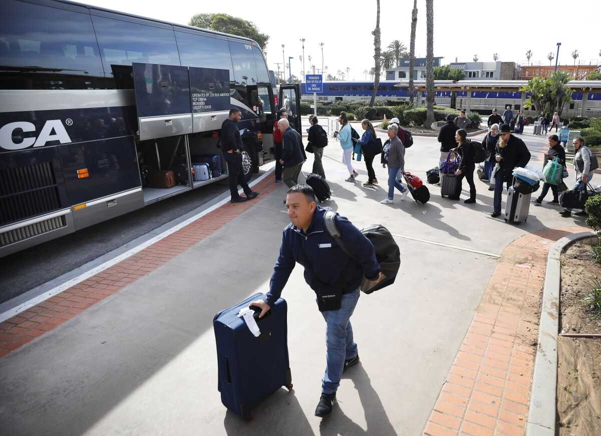 Train passengers walk from an Amtrak train to buses at the Oceanside Transit Center on Thursday.