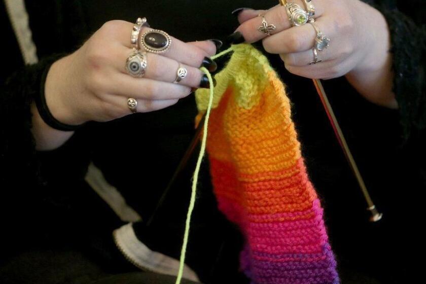 FILE - This April 30, 2018 file photo shows a woman knitting in Silverdale Wash. A free, 8-million strong social network for knitters, crocheters and others in the fiber arts has banned any talk of President Donald Trump and his administration. The new policy on Ravelry.com was posted Sunday, June 23, 2019. The post says the site took the action because it can’t provide a space “inclusive of all and also allow support for open white supremacy.” (Larry Steagall/Kitsap Sun via AP, File)