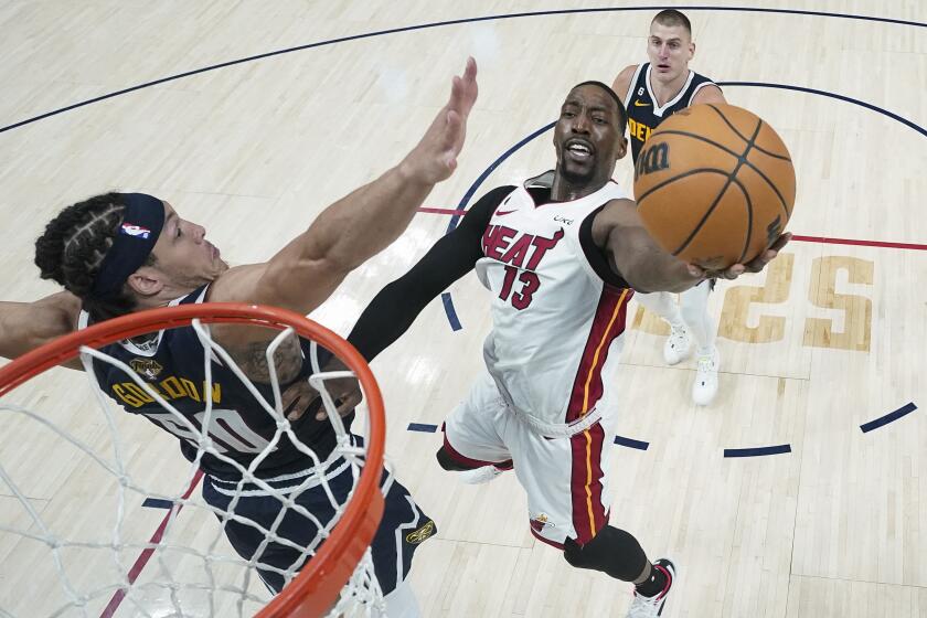 Miami Heat center Bam Adebayo (13) shoots the ball while defended by Denver Nuggets forward Aaron Gordon.