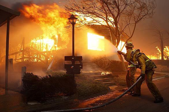 Firefighters pour water on a home in the Oakridge Mobile Home Park in Sylmar. Of the park's 600 homes, 501 were destroyed and at least 40 more sustained serious damage. Best of 2008 Photography >>> Best of 2008 Main >>>