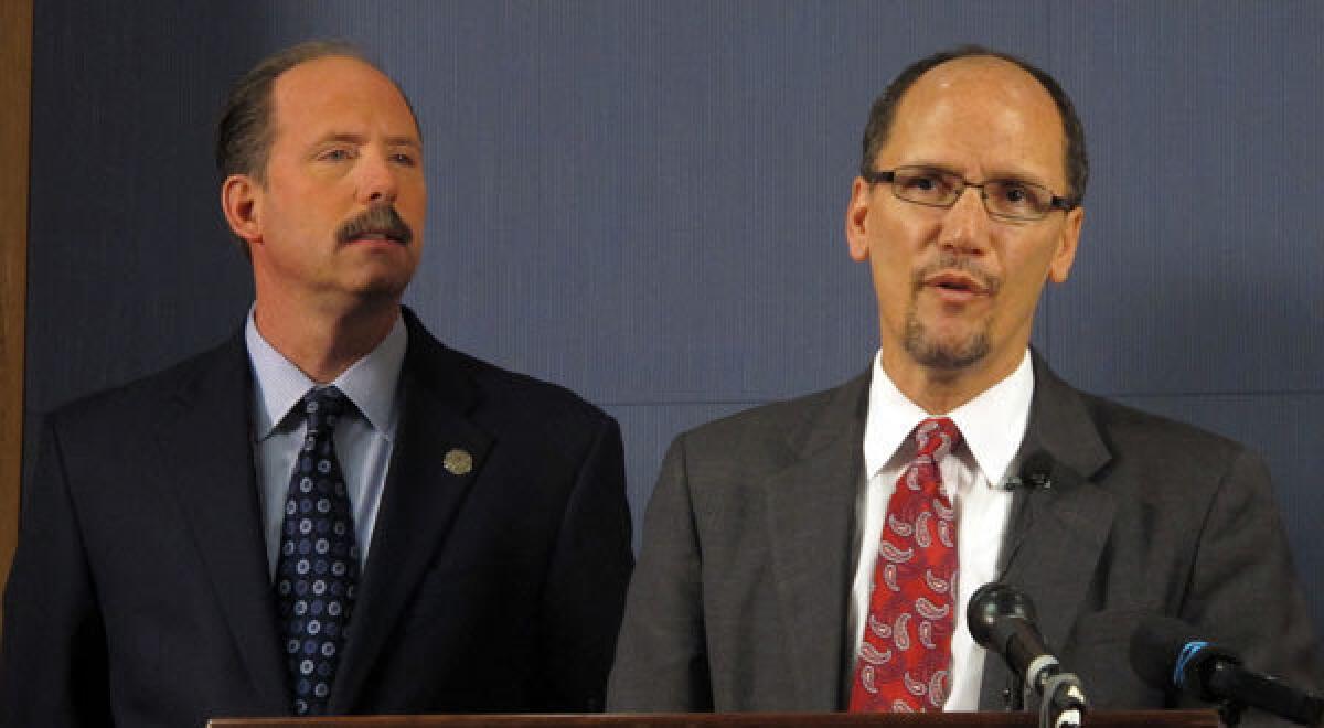 Thomas E. Perez, Assistant Attorney General for the Civil Rights Division is shown with Albuquerque Mayor Richard Berry, left, at a press conference in Albuquerque, N.M.