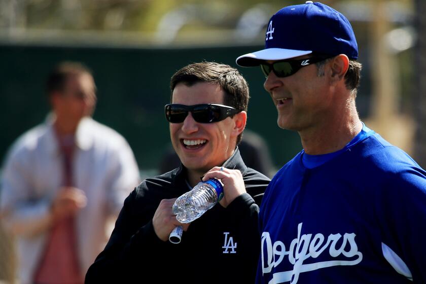 Andrew Friedman, Dodgers' president of baseball operations, shares a light moment with Manager Don Mattingly during a workout Friday. Now they have to set their roster for opening day.