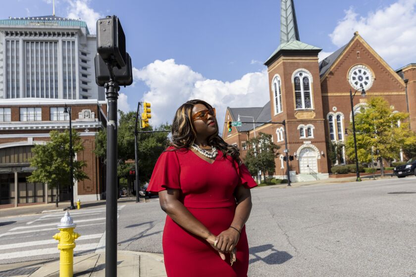 Khadidah Stone stands on the dividing line between her old Alabama congressional District 7, to her right with River City Church, and her new district, District 2, to her left, in downtown Montgomery, Ala., Tuesday, Sept. 20, 2022. The line splits Montgomery between two congressional districts and is the subject of a high-stakes case that will go before the U.S. Supreme Court on Tuesday. (AP Photo/Vasha Hunt)