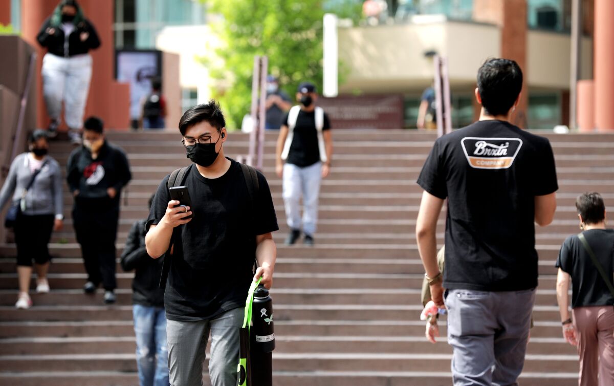 A person wearing a face mask walks in front of stairs.