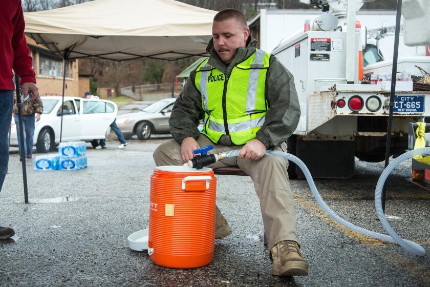 Brian Oxley, chief of police in Oxley, W.Va., helps local residents fill water containers Saturday following the chemical spill Thursday in Charleston, W.Va.