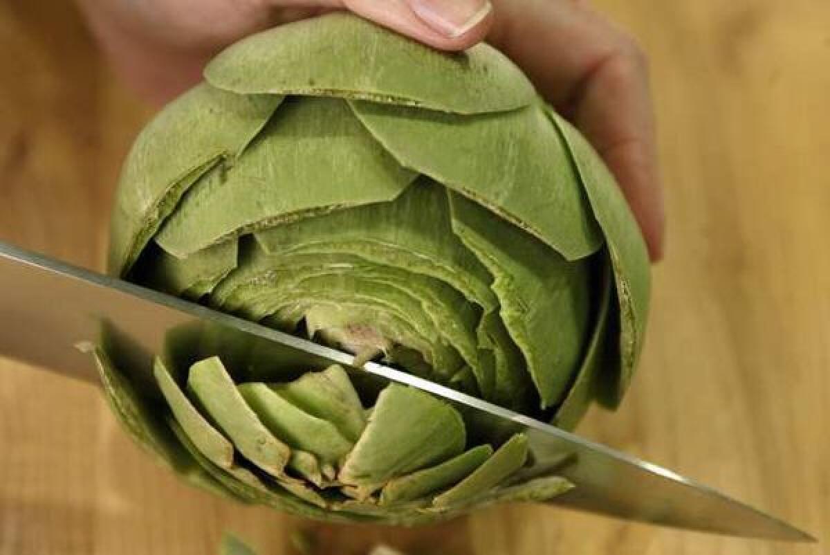 Cleaning an artichoke: Removing the top of the head.