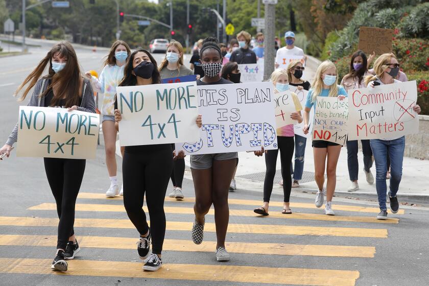 Students walk along Eastbluff Drive in front of Corona Del Mar High as they rally with parents and teachers against of the new "4x4" learning schedule adopted by Newport-Mesa Unified School District recently. The model, or schedule is for the 2020-21 school year.