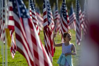 PALMDALE, CA - NOVEMBER 11: Mary Bailey, 8, pauses at one of 2020 American flags flying over the Palmdale Healing and Honor Field at Pelona Vista Park honoring veterans on Wednesday, Nov. 11, 2020 in Palmdale, CA. (Brian van der Brug / Los Angeles Times)