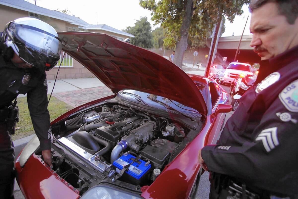 Officer Will Durr, left, and Sgt. Greg Fuqua, members of the Los Angeles Police Department’s Aggressive Driving Detail, inspect the illegal modifications a motorist had made to his vehicle in Granada Hills.