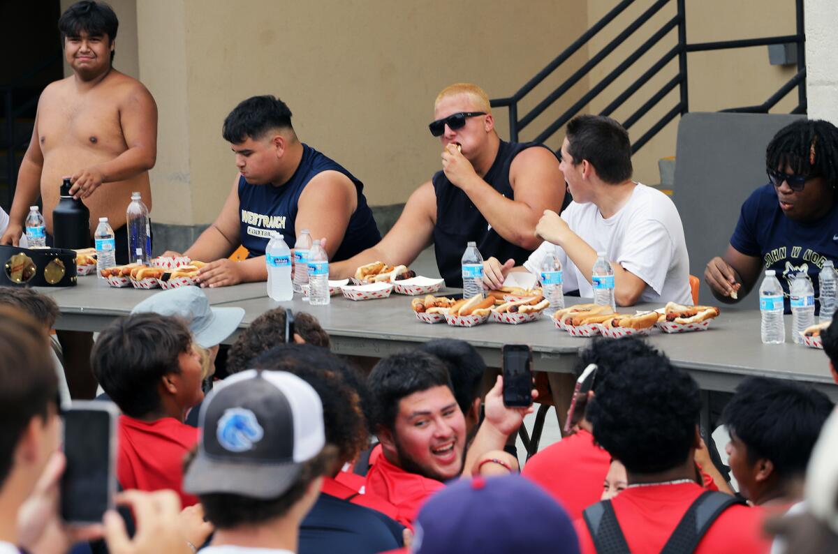 Huntington Beach's Sean Marella, center, competes in the hotdog eating contest at the Surf City passing tournament.