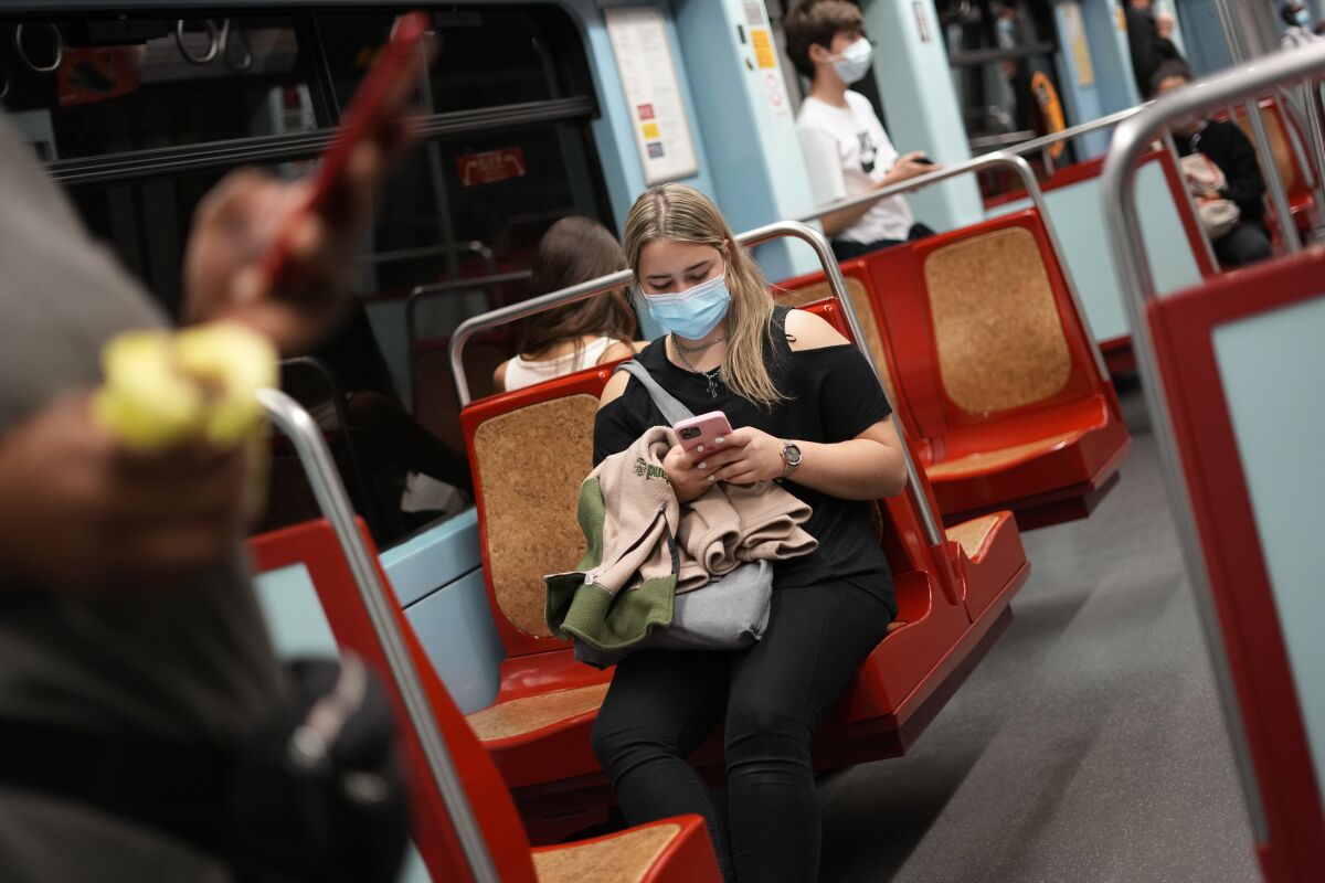 File - A woman wearing a face mask uses her cellphone in a subway train in Lisbon, on Oct. 22, 2021. Portugal has inoculated 86% of the country against COVID-19, but its prime minister is warning that a recent surge in infections across Europe compels it to consider taking precautionary measures. The government has convened a meeting of health experts on Friday to assess what measures may be required. (AP Photo/Armando Franca, File)