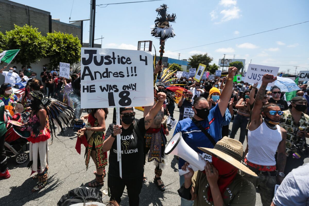 A crowd of protesters, some with fists raised and holding signs. One sign reads, "Justice 4 Andres!!! He was only 18."