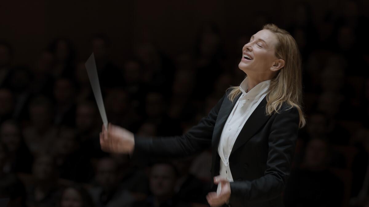 A woman waves a baton as she conducts an orchestra in a scene from "Tár."