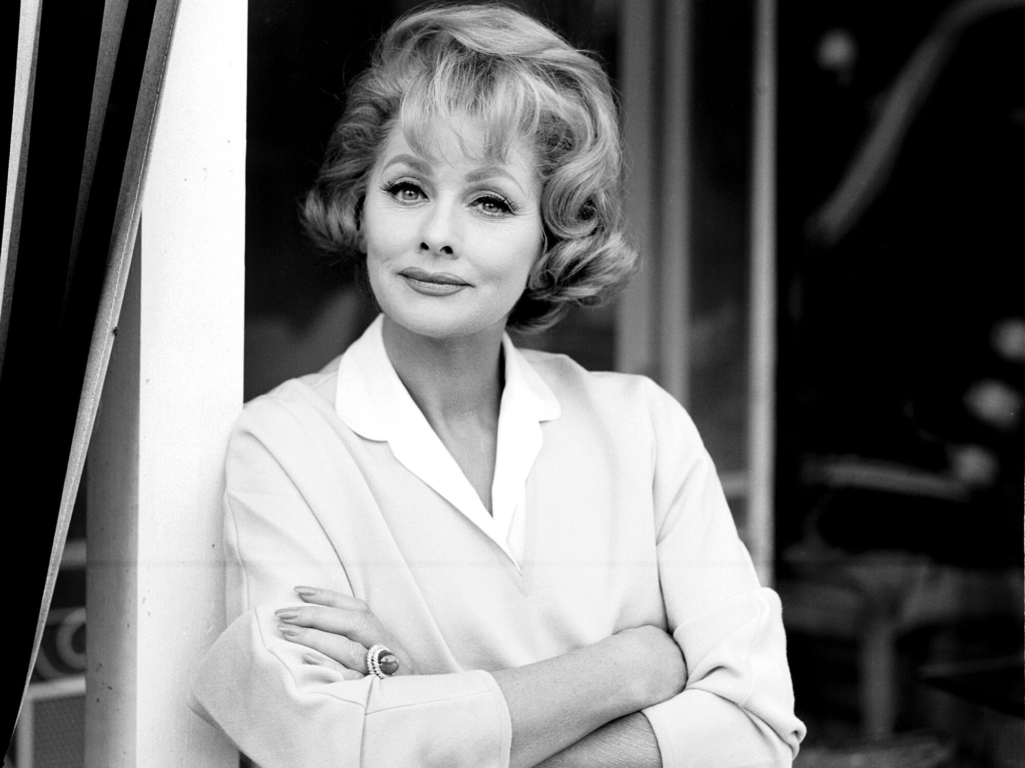A black-and-white portrait of Lucille Ball leaning against a post.