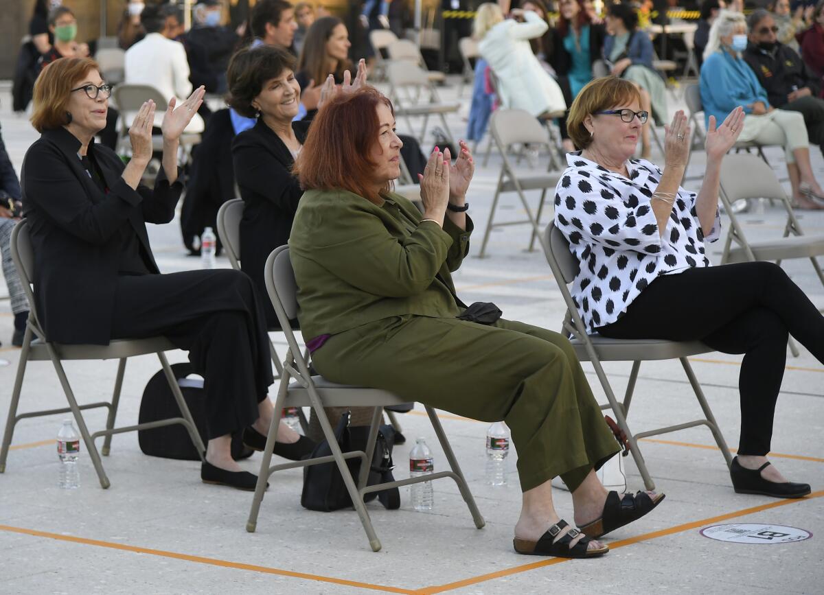 Women sit in metal folding chairs on the Music Center plaza.