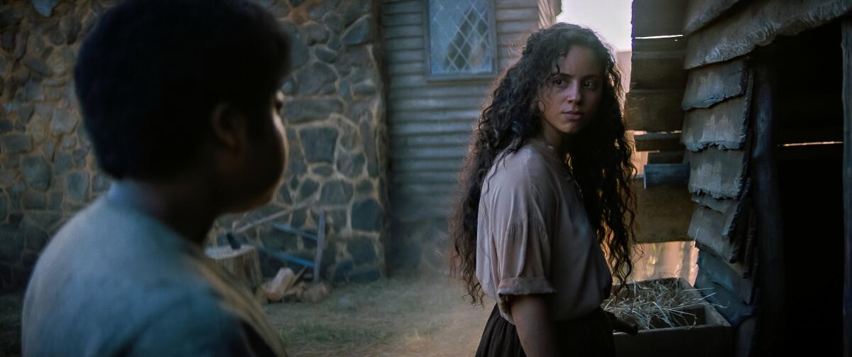 Benjamin Flores Jr. and Kiana Madeira look at each other in a scene from "Fear Street Part 3: 1666."