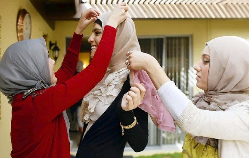 Nora Diab, left, and Marwa Atik adjust a new hijab on friend Marwa Biltagi in the backyard of Atik's home.