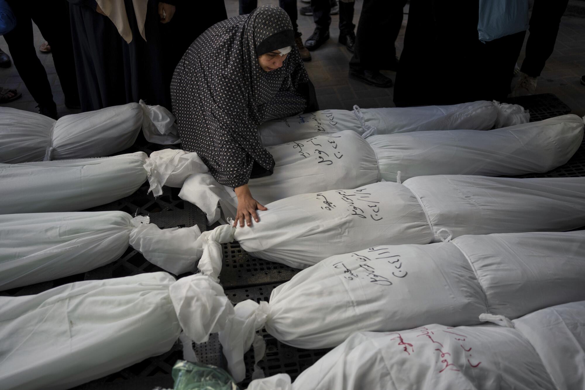 Palestinians mourning enshrouded relatives killed in Israel's bombardment of Gaza