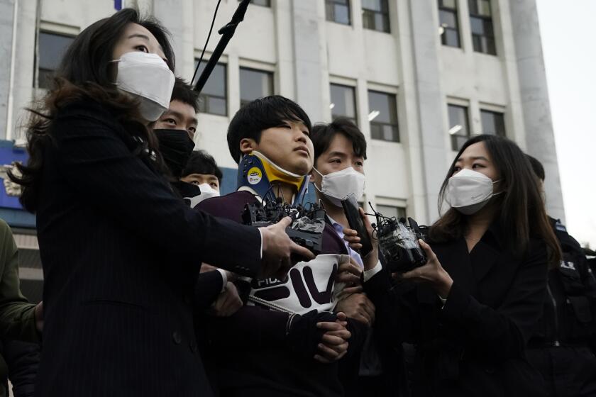 Cho Ju-bin, center, leader of South Korea's online sexual blackmail ring which is so called "Nth room," is surrounded by journalists while walking out of a police station as he is transferred to prosecutors' office for further investigation in Seoul, South Korea, Wednesday, March 25, 2020. South Korean prosecutors on Wednesday began reviewing whether to formally charge a man arrested last week on allegations he operated secretive chatrooms where he posted sexually abusive videos of blackmailed women in return for cryptocurrency payments. (Kim Hong-Ji/Pool Photo via AP)