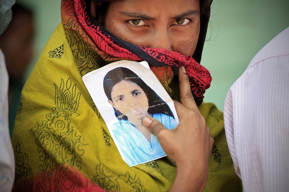 A woman holds a photo of her missing sister on Friday, nine days after a building collapsed in Savar, Bangladesh.