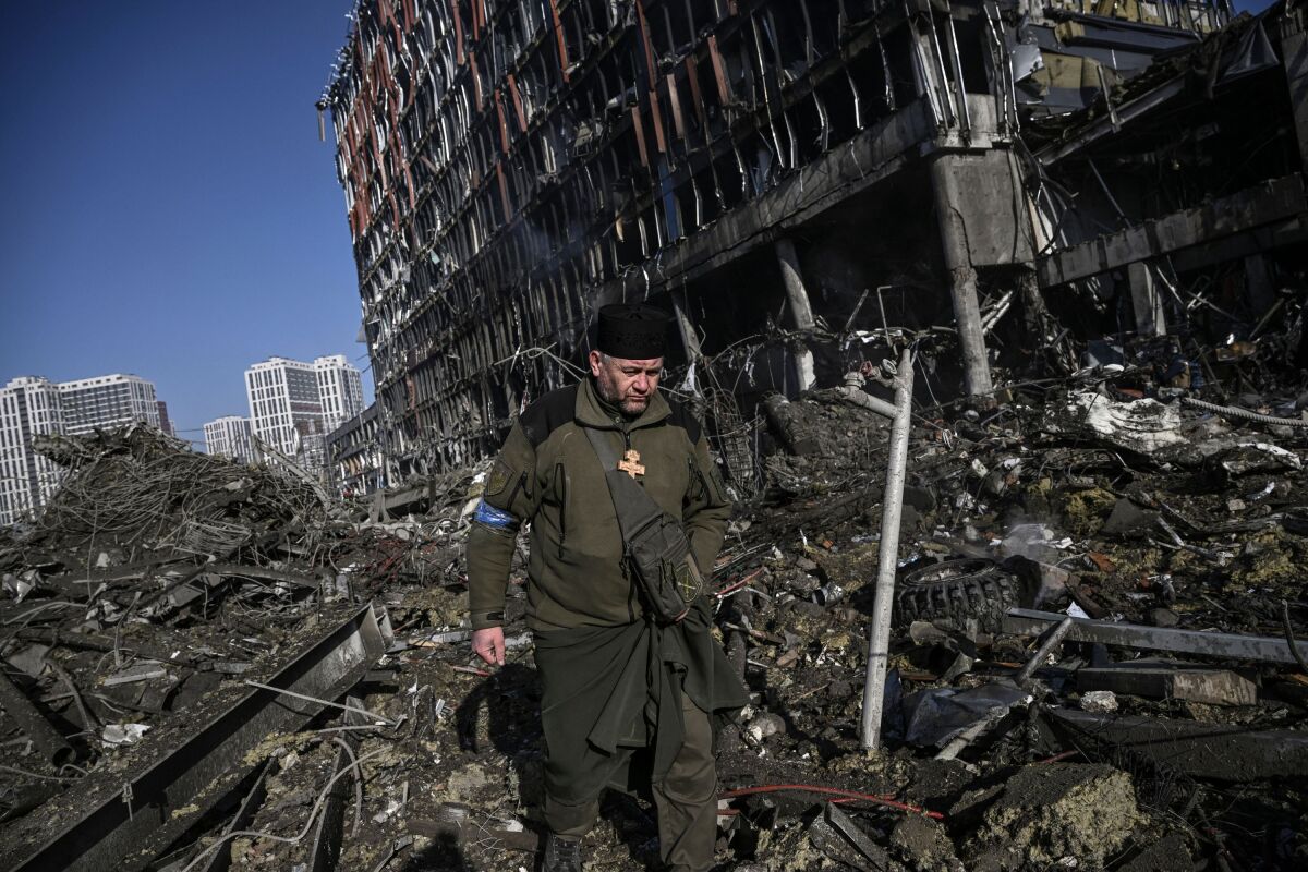 A Ukrainian army chaplain walks through rubble