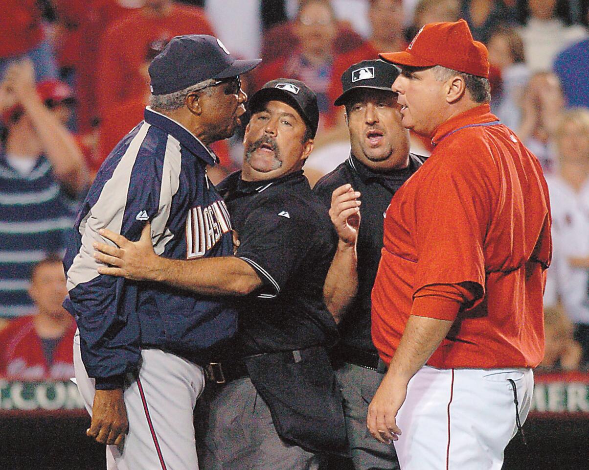 Washington Nationals' Frank Robinson, left, is held back by umpire Tim Tschida as umpire Dale Scott holds back Los Angeles Angels coach Mike Scioscia after Angels pitcher Brendan Donnelly was ejected in the seventh inning for having a foreign substance in his glove Tuesday, June 14, 2005, in Anaheim.