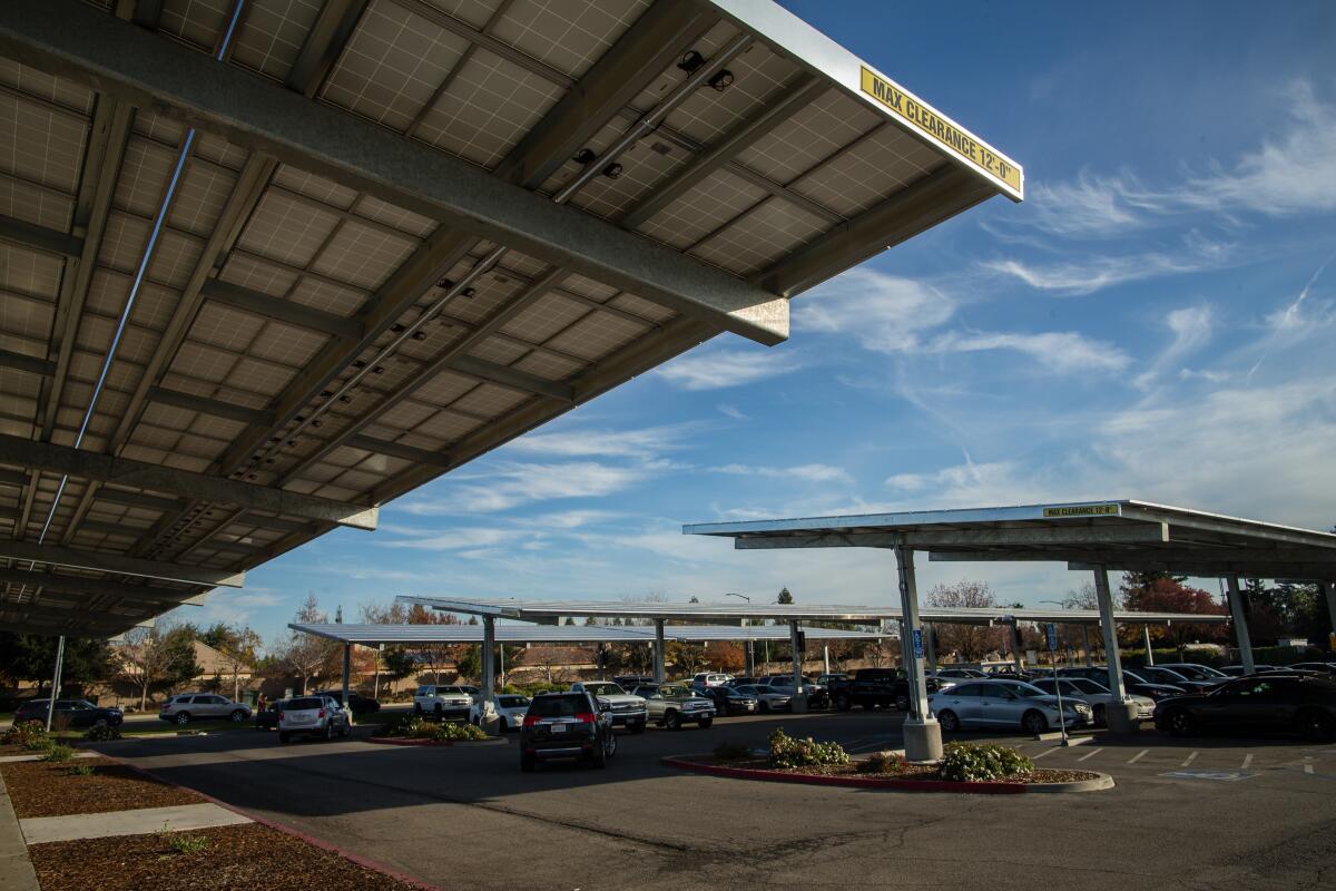 Solar panel structures provide shade to vehicles in a parking lot 