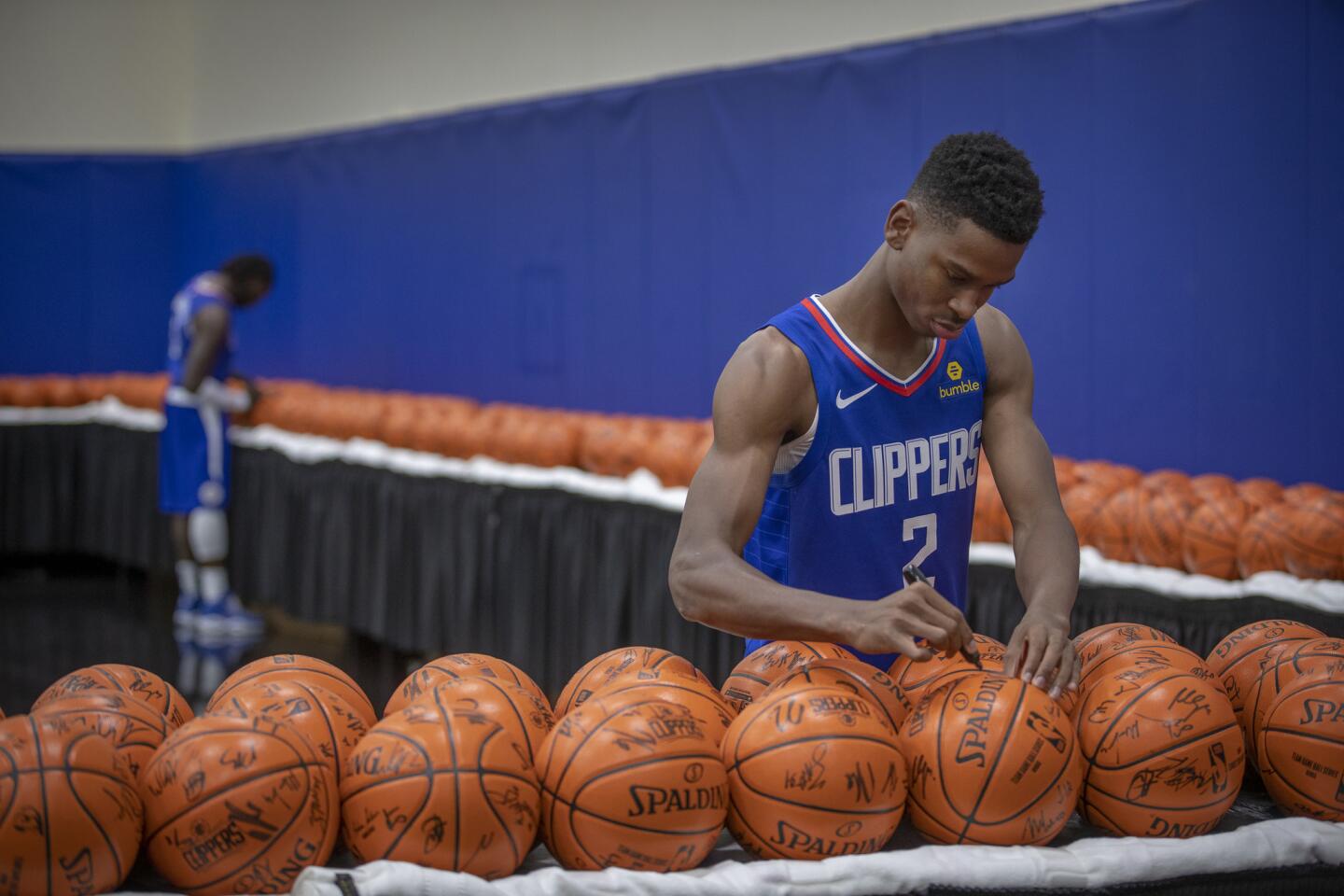 Clippers rookie guard Shai Gilgeous-Alexander (2) and teammate Montrezl Harrell sign basketball during media day in Playa Vista.
