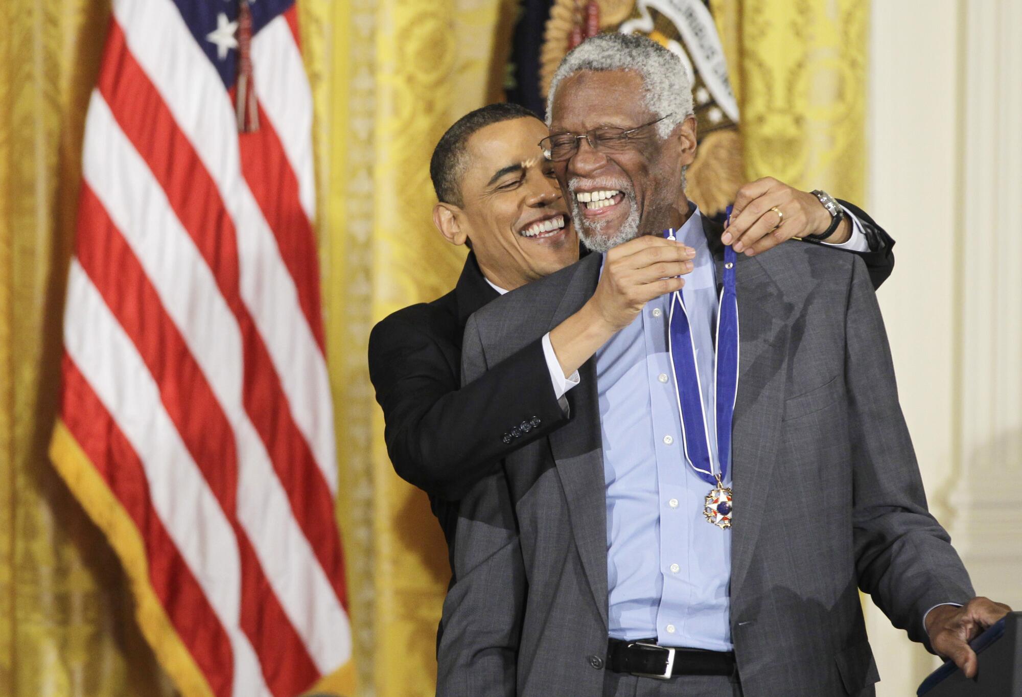 President Barack Obama reaches up to present a 2010 Presidential Medal of Freedom to NBA legend Bill Russell.