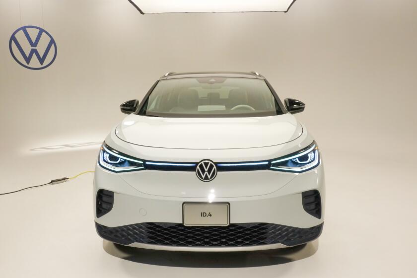 The all-electric Volkswagen ID.4 compact SUV shown from the front in a well-lit studio. The headlight area has blue-light highlights as a design element.
