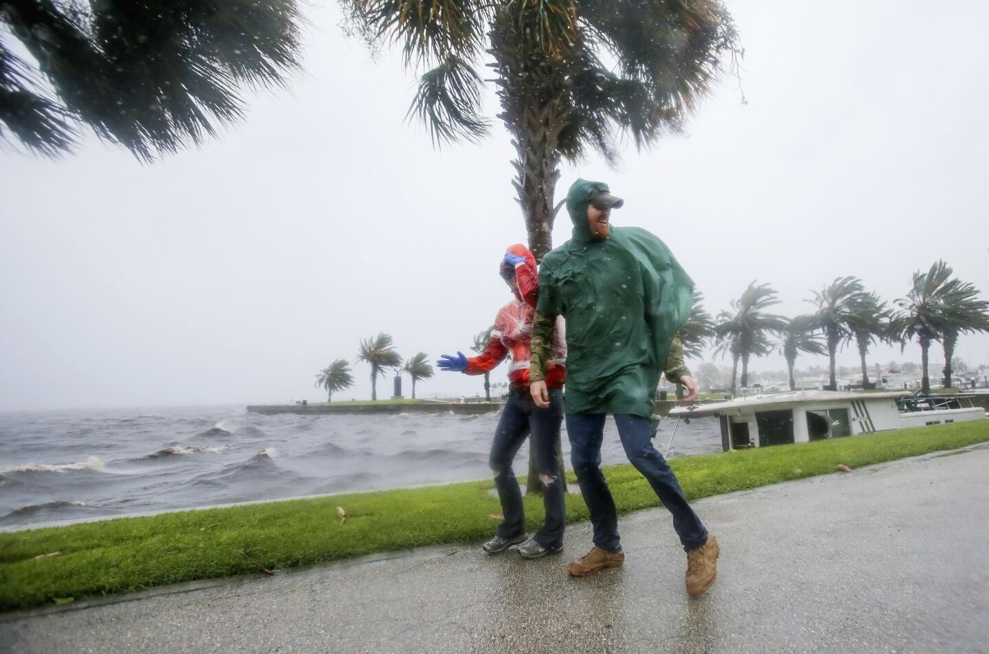 A couple walk along Lake Monroe amid strong winds and rain from Hurricane Matthew in downtown Sanford, Fla., on Oct. 7, 2016.