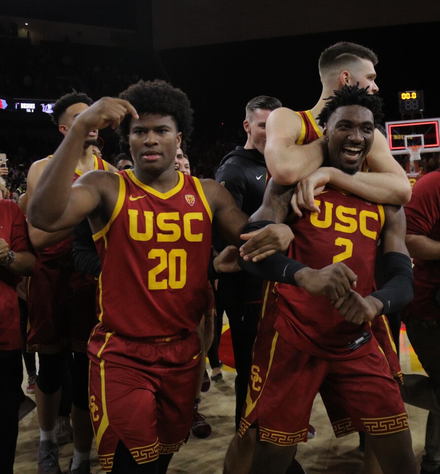 LOS ANGELES, CA - MARCH 7, 2020: USC Trojans guard Jonah Mathews (2) is swarmed by teammates USC Trojans guard Ethan Anderson (20) and USC Trojans forward Nick Rakocevic (31) after scoring the game winning 3-point shot to beat UCLA in the final moments at Galen Center on March 7, 2020 in Los Angeles, California. (Gina Ferazzi/Los AngelesTimes)