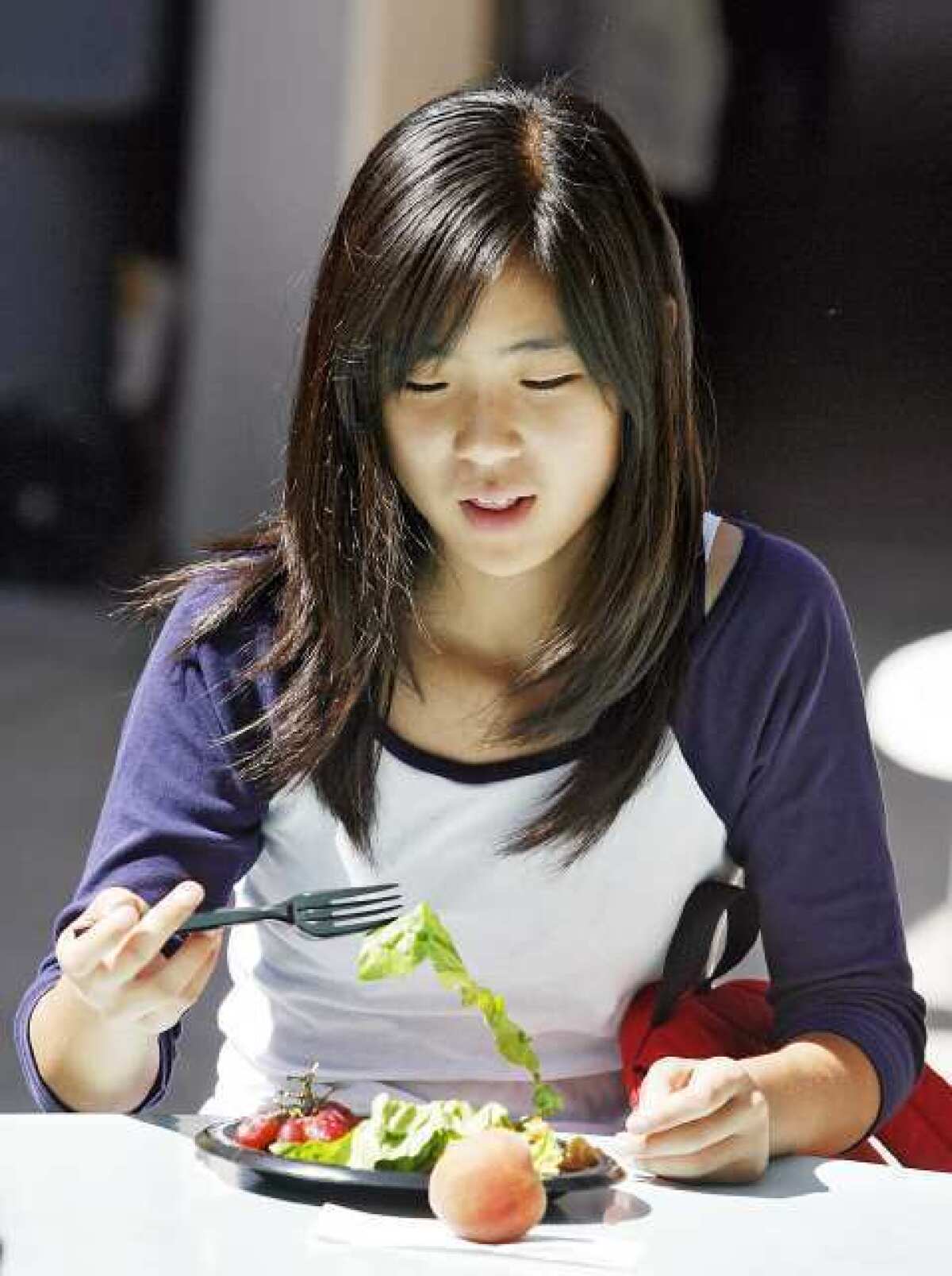 Nika Kim, 13, lifts a piece of lettuce, which is considered a vegetable, during lunchtime at Rosemont Middle School in La Crescenta. Federal guidelines for school lunches mandates a healthier menu, including whole grain pastas, low fat cheese, and every student must take one-half cup of fruit or vegetables per day.