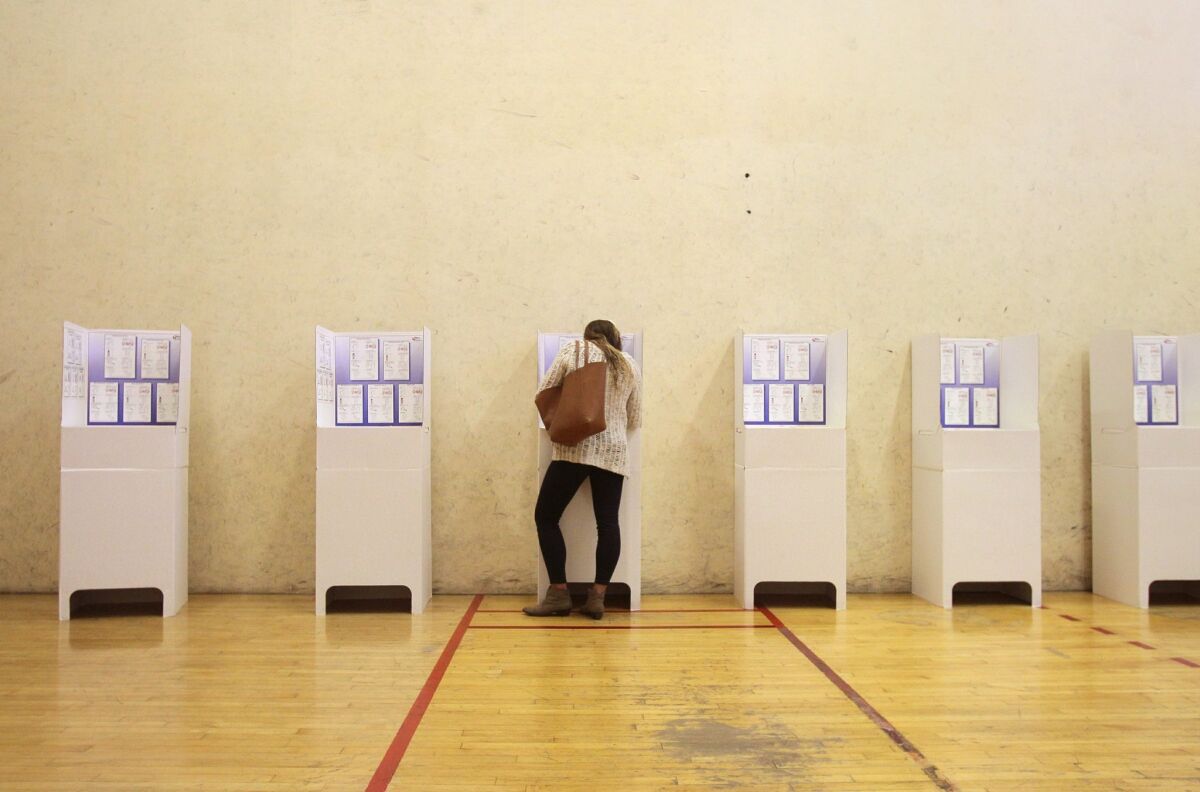 A voter fills out her ballot at the polling place at Encinitas Boxing & Fitness. The room has been used as a basketball court and racket ball court.