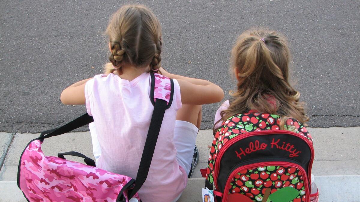 Two girls wait on the sidewalk on the first day of the school year on August 12, 2008.