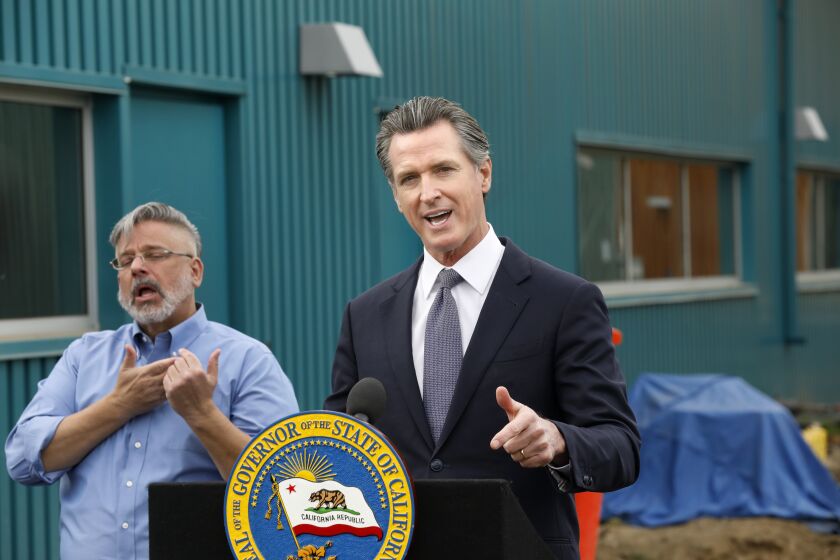 Los Angeles, California-Jan. 31, 2022-On Jan, 31, 2022, California Governor Gavin Newsom holds a press conference after taking a tour of the site of a behavioral health and transitional housing facility in Los Angeles County, at 1326 W Imperial Hwy., to highlight the state's major new investments to house and provide critical support services to the most vulnerable Californians. At let is ASL interpreter Richard Dickinson. (Carolyn Cole / Los Angeles Times)