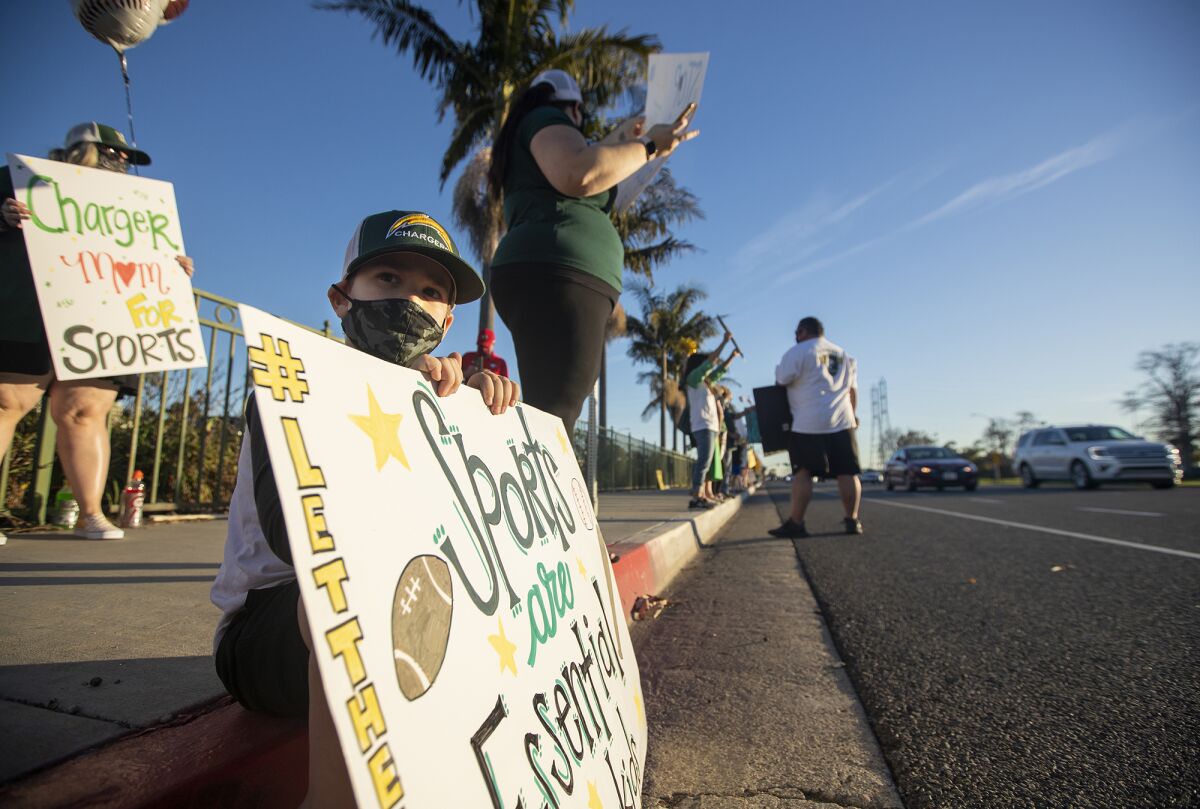 Wyatt Braddock, 5, with his mom Amy, participate in a "Let Them Play" rally at Edison High School on Friday.