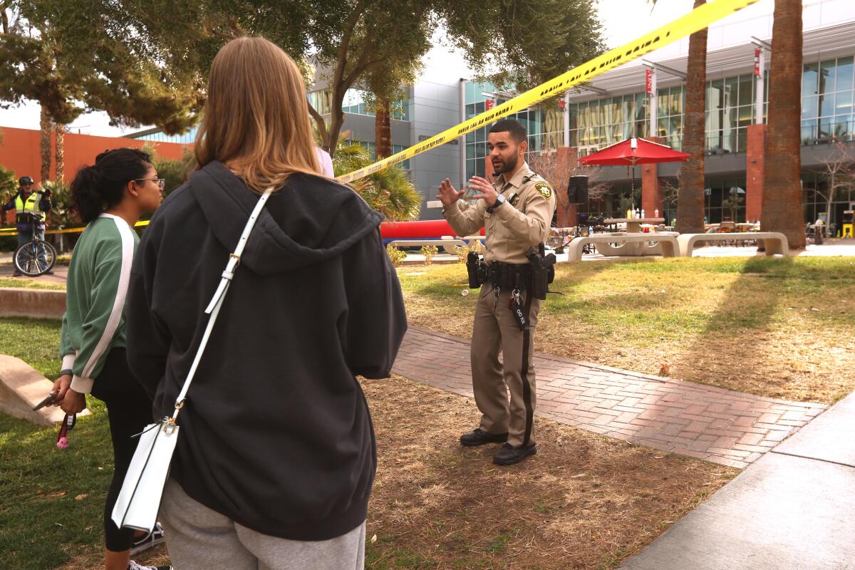 A police officer talks with students near the Student Union, background, 