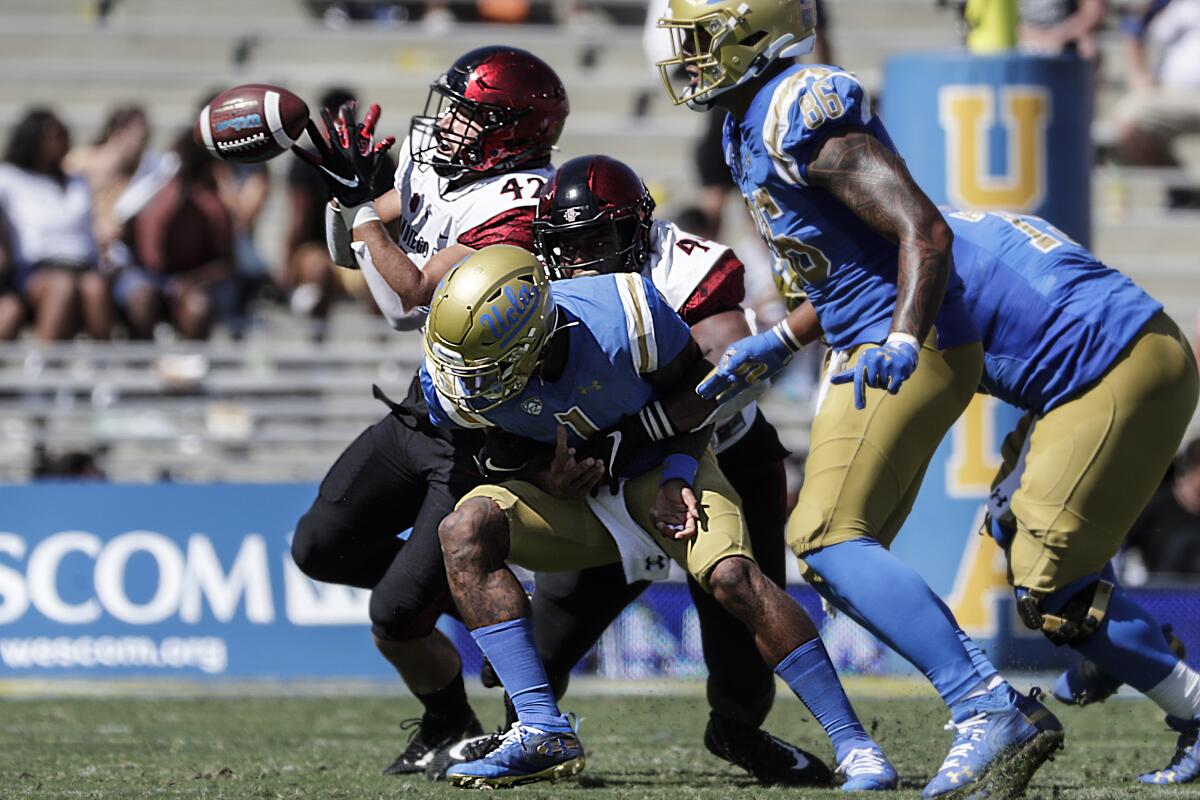 UCLA quarterback Dorian Thompson-Robinson passes under pressure from San Diego State rushers Kyahva Tezino and Keshawn Banks during second quarter action at the Rose Bowl on Saturday.
