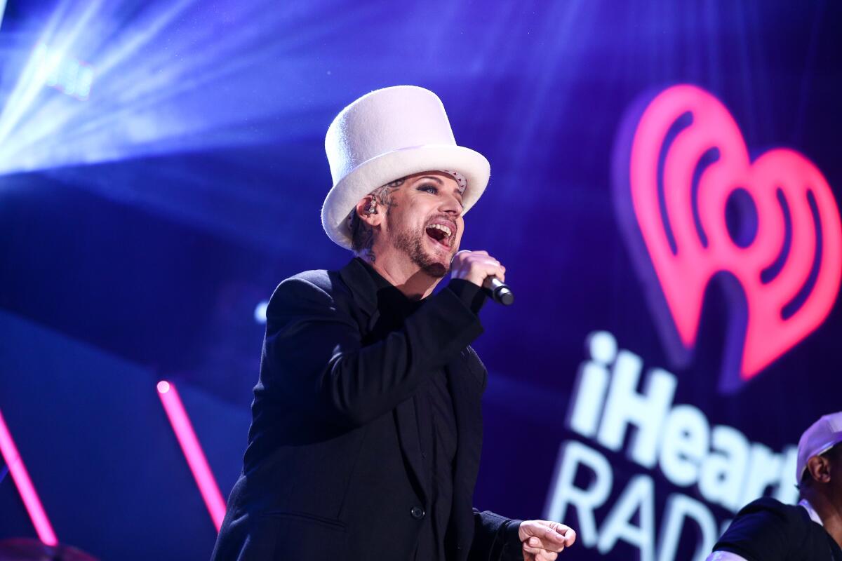 Boy George singing onstage in a white top hat