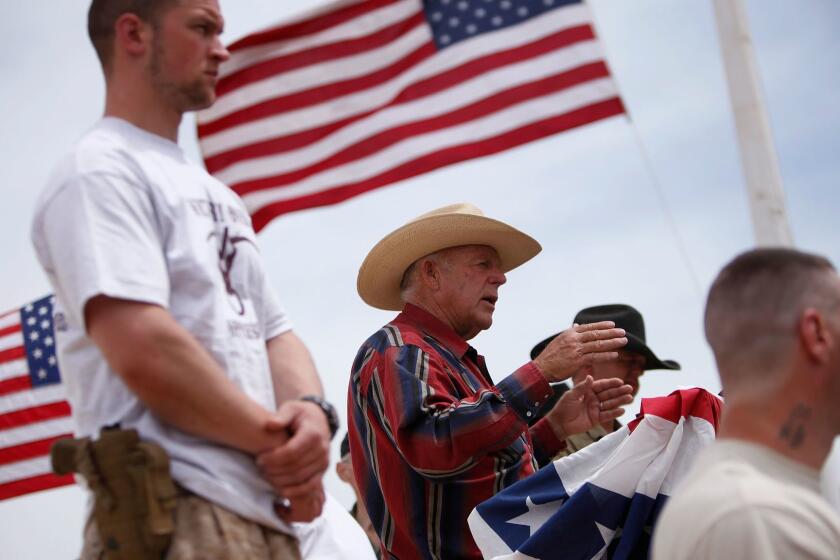 FILE - In this April 18, 2014, file photo, rancher Cliven Bundy, flanked by armed supporters, speaks at a protest camp near Bunkerville, Nev. Federal prosecutors will try again to convince a jury that four men conspired with Nevada rancher Bundy and his family when they took up arms during a 2014 standoff that stopped federal agents from confiscating cows belonging to the states' rights advocate. July selection begins Monday, July 10, 2017. (John Locher/Las Vegas Review-Journal via AP, File)