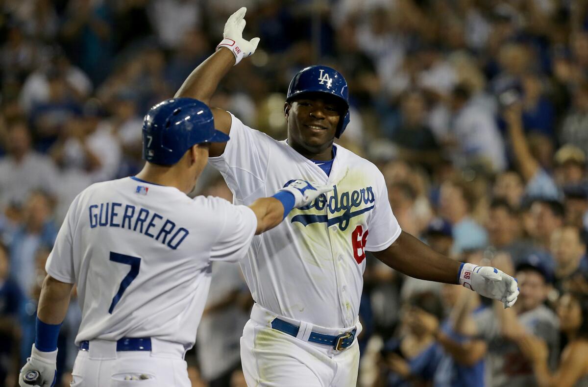 Dodgers outfielder Yasiel Puig is congratulated by teammate Alex Guerrero after hitting a two-run homer against the Oakland Athletics during the fourth inning of a game Wednesday.