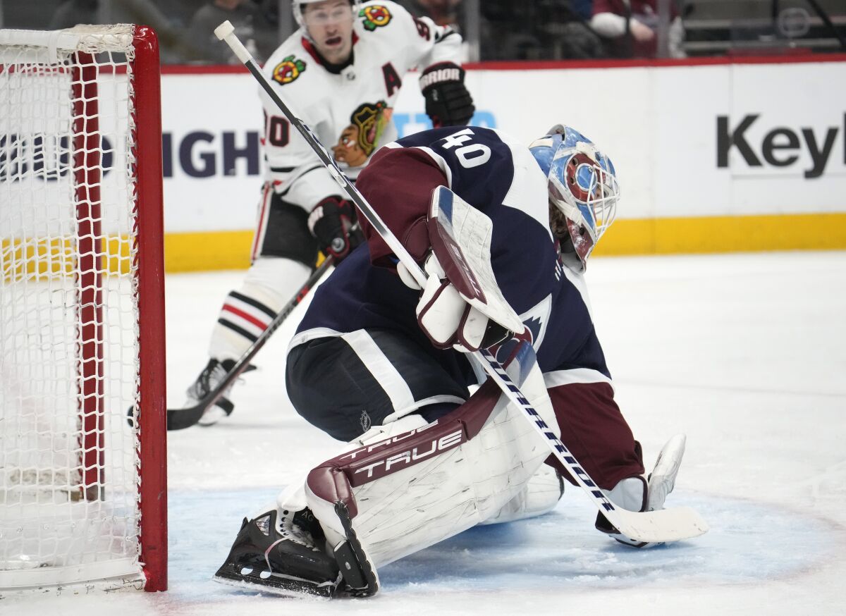 Colorado Avalanche goaltender Alexandar Georgiev, front, makes a glove save of a shot as Chicago Blackhawks center Tyler Johnson covers in the second period of an NHL hockey game Monday, March 20, 2023, in Denver. (AP Photo/David Zalubowski)