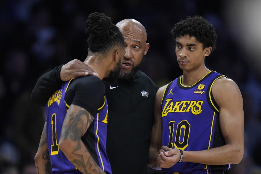 Los Angeles Lakers head coach Darvin Ham, center, talks with guards D'Angelo Russell (1) and Max Christie (10) during the first half of an NBA basketball game against the Milwaukee Bucks, Friday, March 8, 2024, in Los Angeles. (AP Photo/Jae C. Hong)